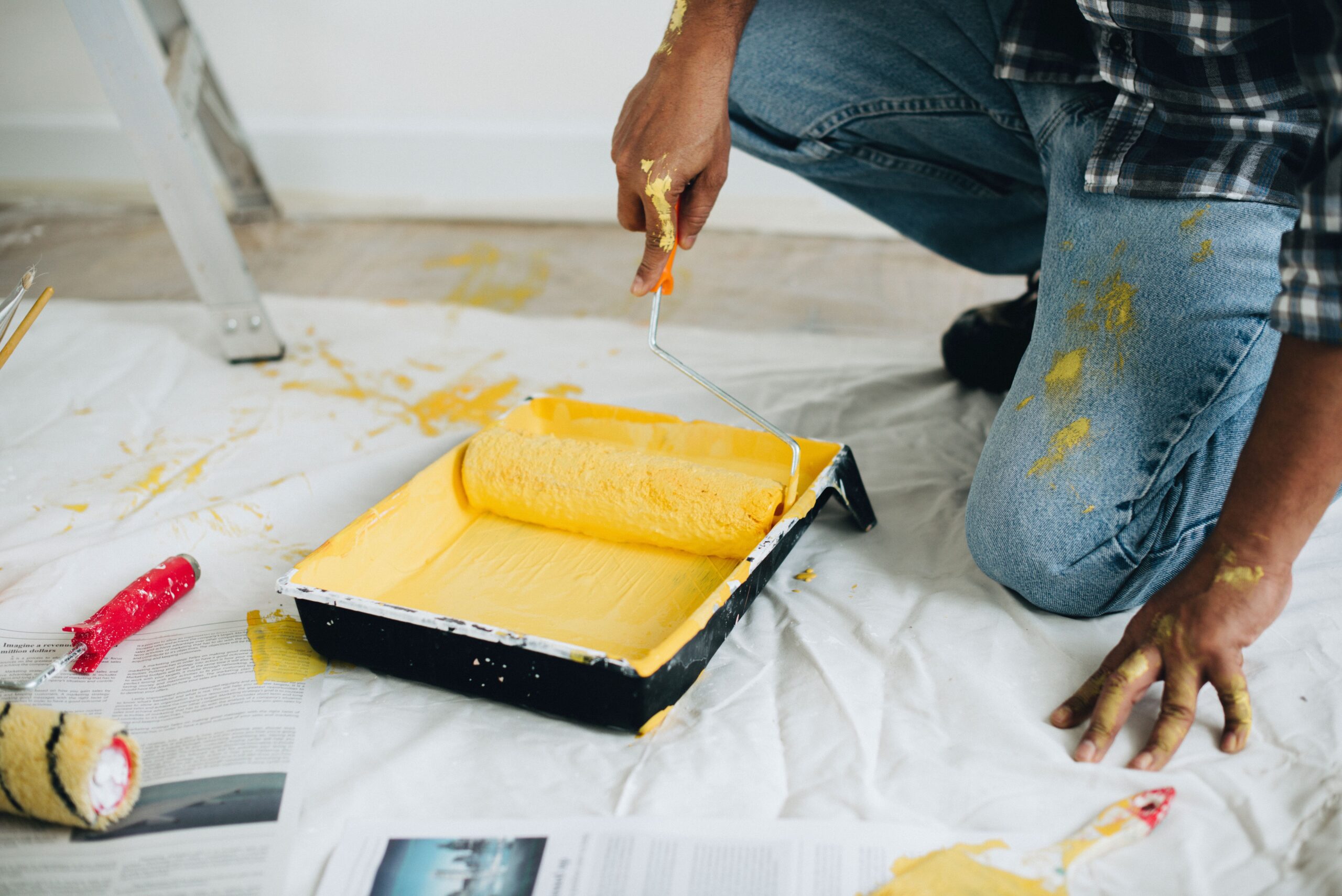 guy using a roller on a yellow paint