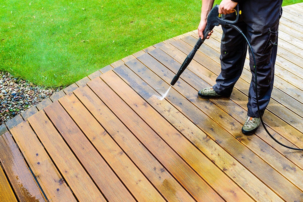 guy pressure washing patio deck