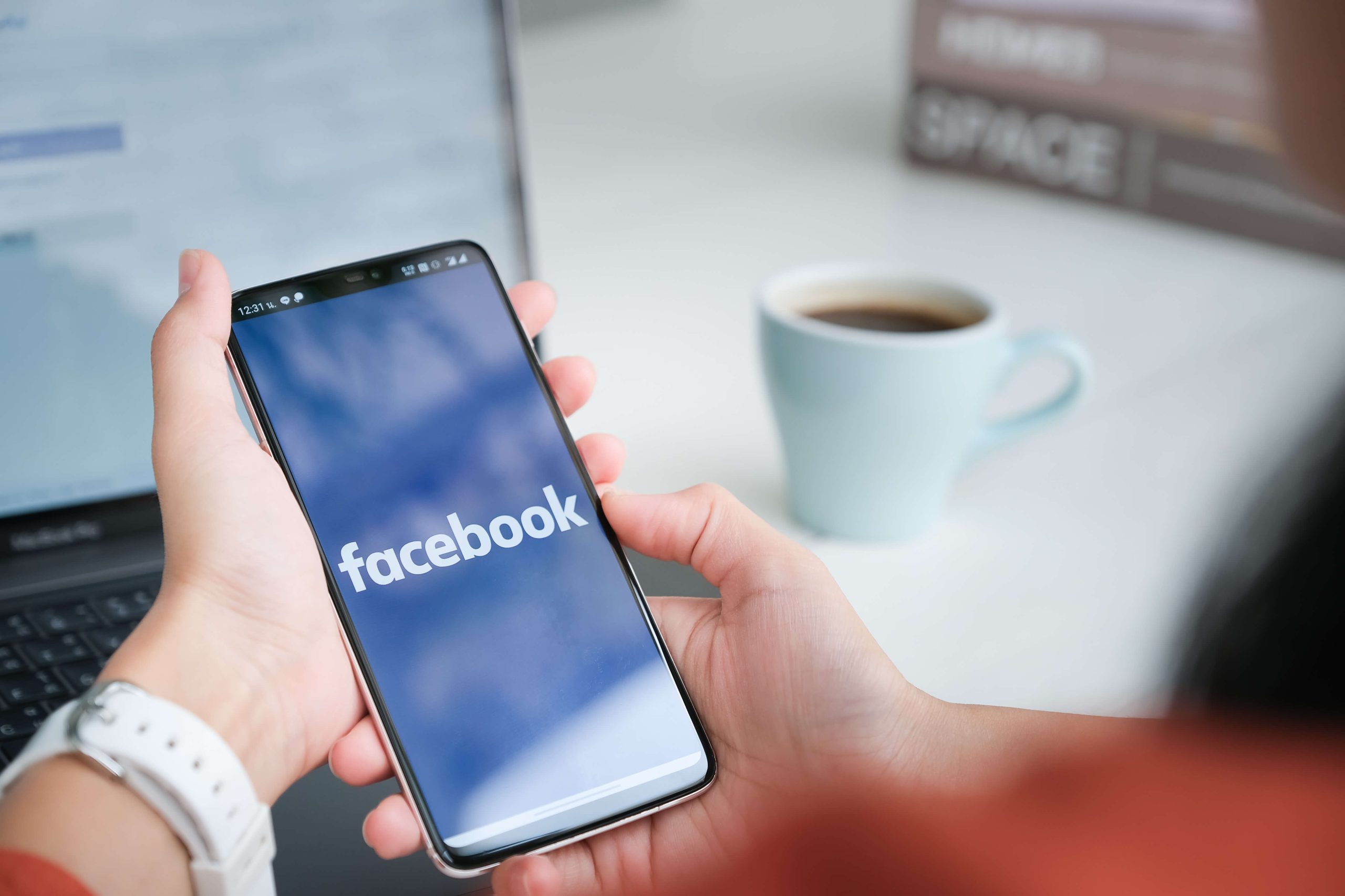 woman holds phone with facebook application on screen